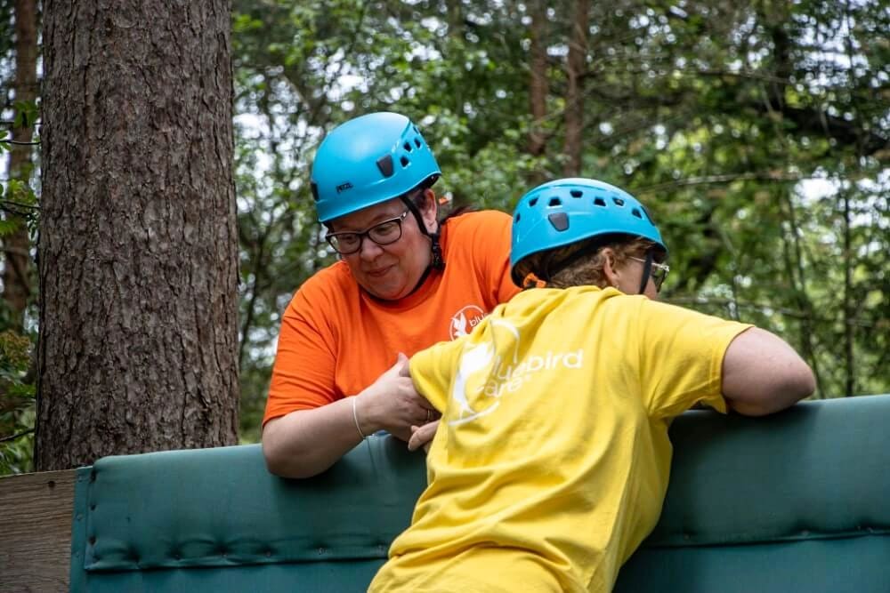 Two women working as a team to overcome an obstacle challenge at New Forest Activities